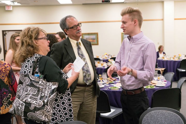A student talking to scholarship donors at a luncheon.