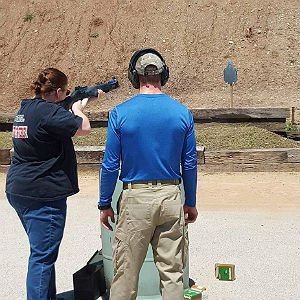 A criminal justice student fires a shotgun at a gun range.