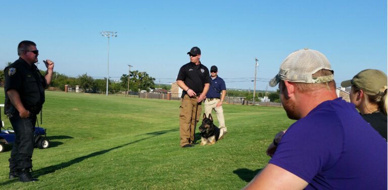 Criminal justice majors watch police officers with a police dog perform a demonstration.