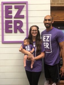 Meguell and Brittany Suell stand in front of their company's logo with their youngest child.