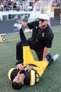 Glenn Revell helps a player stretch on the sidelines.