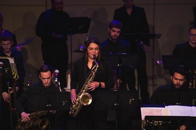 A female student plays the saxophone during a jazz ensemble performance.