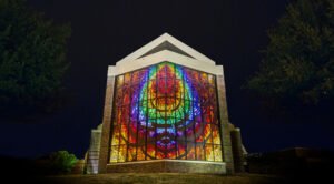 The Logsdon Chapel stained glass window shines brightly at night.