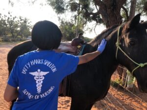 A Patty Hanks student cares for a Camp Able horse.