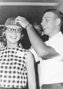 A junior helps a freshman adjust her beanie in 1964.