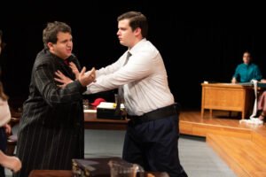 Felippe Decker, playing the part of Baliff, prevents "Guts" Regan, played by Tony Barone, from barging in the courtroom.