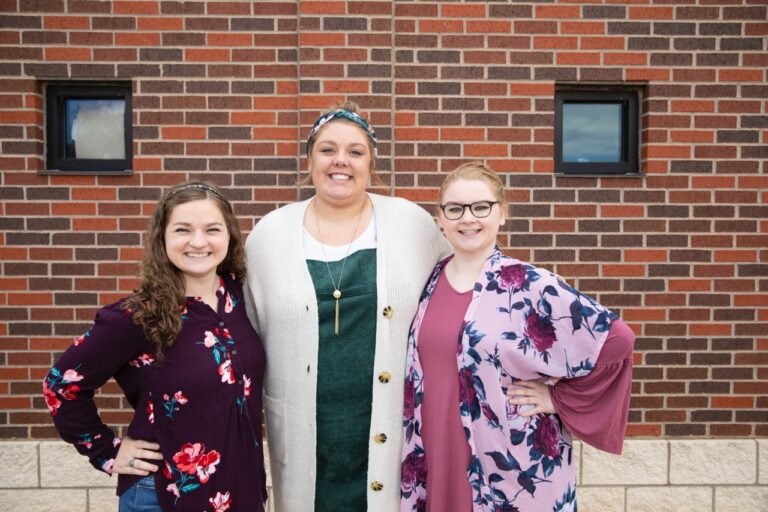 Grace Sosa, Macee Hall, and Felicity Neptune pose in front of the HSU Marketing office.