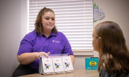 A grad student works with a client at the SLP clinic.