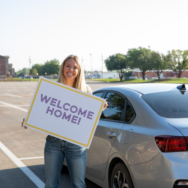 Young woman with a Welcome Home sign.