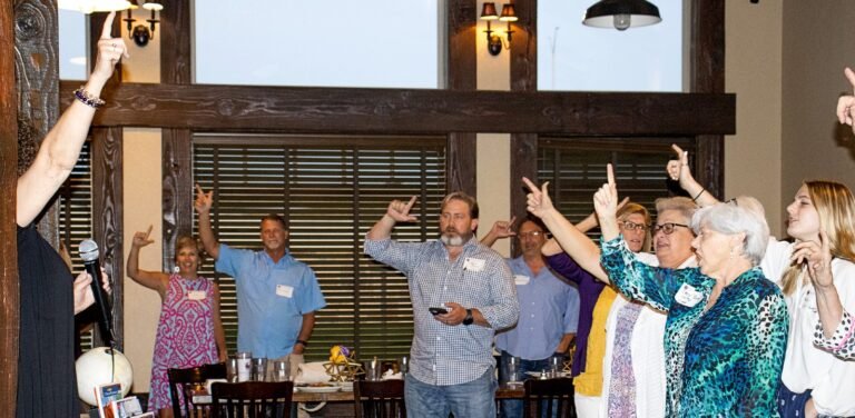 Alumni sing the fight song at a dinner.