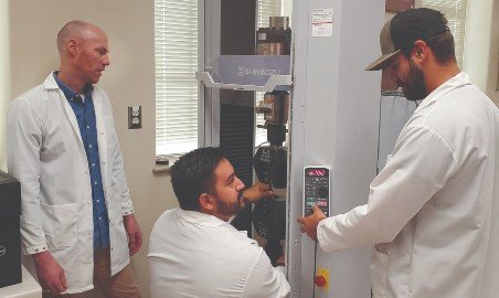 Professors work on a machine in the engineering lab.