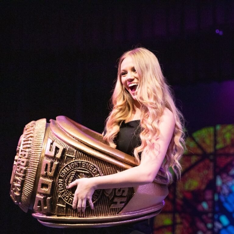 Female student at ring ceremony poses with giant ring.