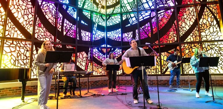 Chapel band performing in front of the stained glass window.