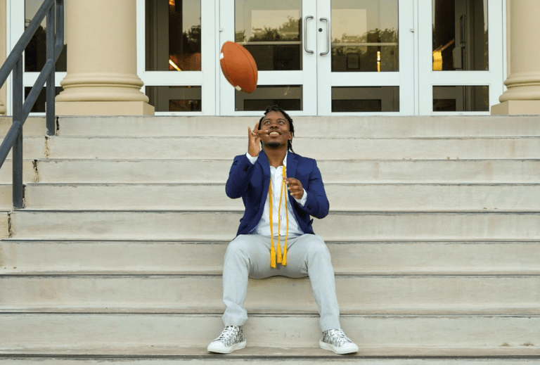 Demarcus Coleman sitting on the steps with a football