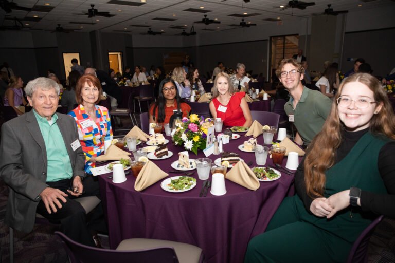 Students and donors sit at a table during the scholarship luncheon.