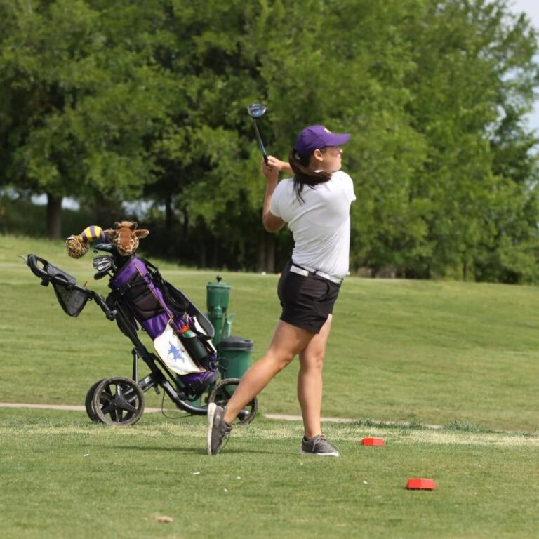 An HSU female golfer swinging.