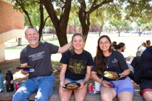 Students and faculty sit outside, enjoying lunch