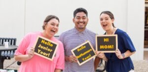 Three students pose with signs.