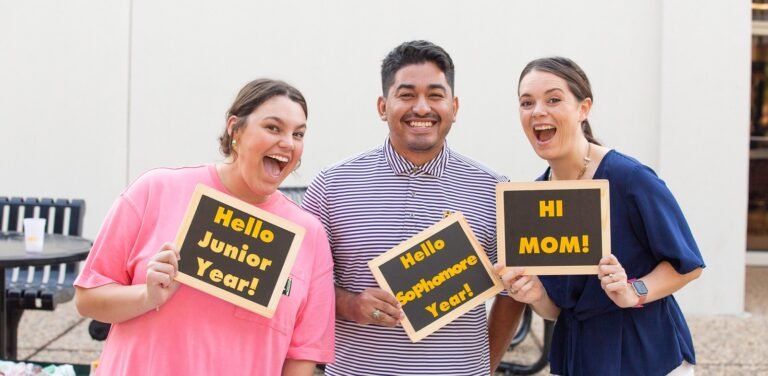 Three students pose with signs.