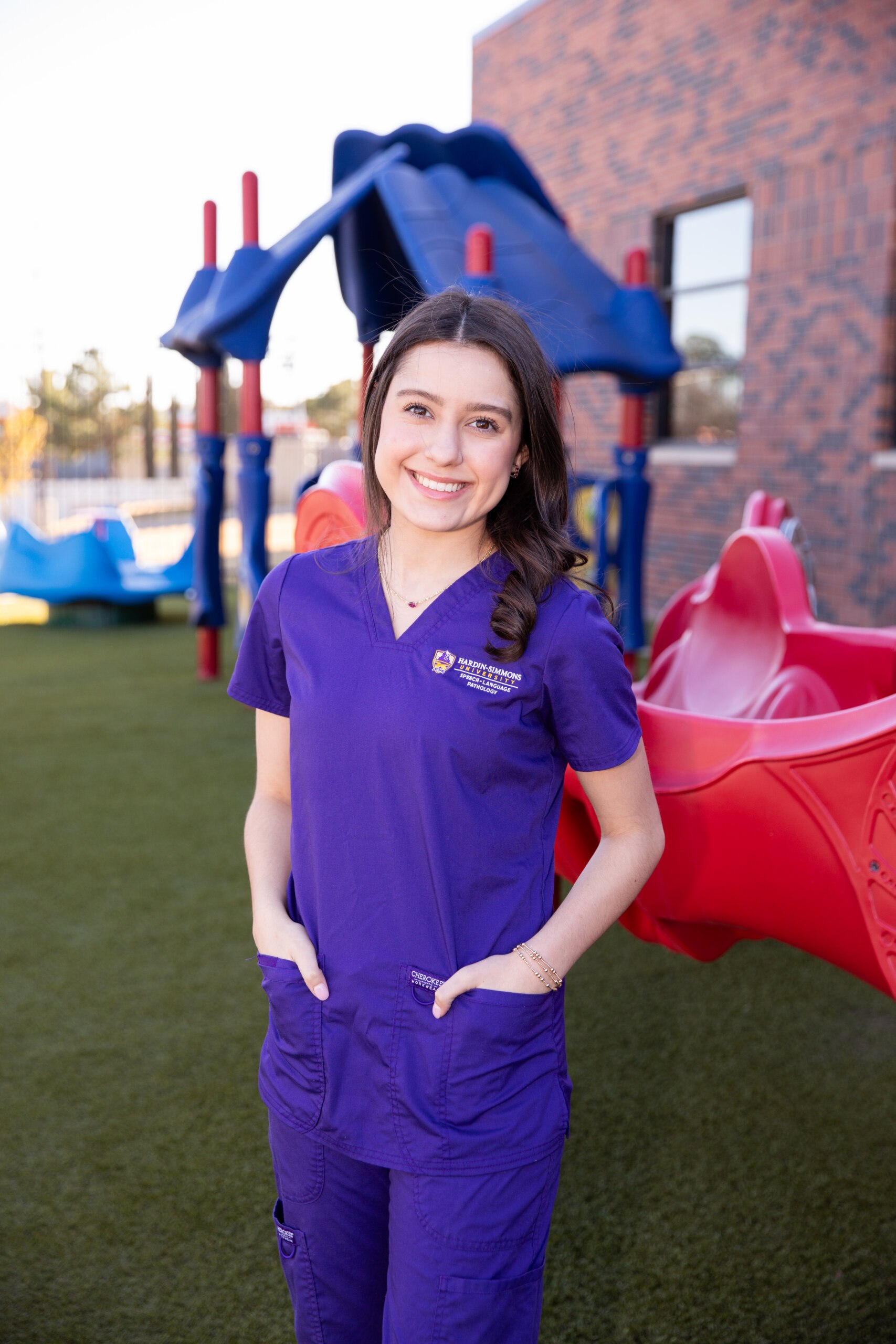Speech-Language Pathology student standing infront of the playground at the clinic.