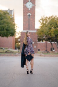 Emily Uhl with her graduation gown stands in front of the clocktower on campus.