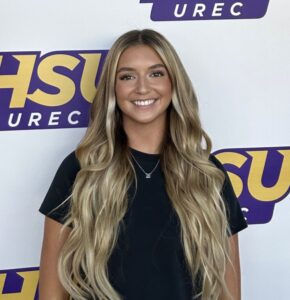 Raylee Bevill stands in front of an HSU sign.