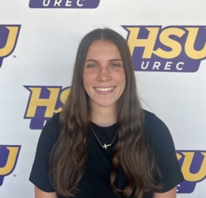 Madalyn Varnell standing in front of an HSU sign.