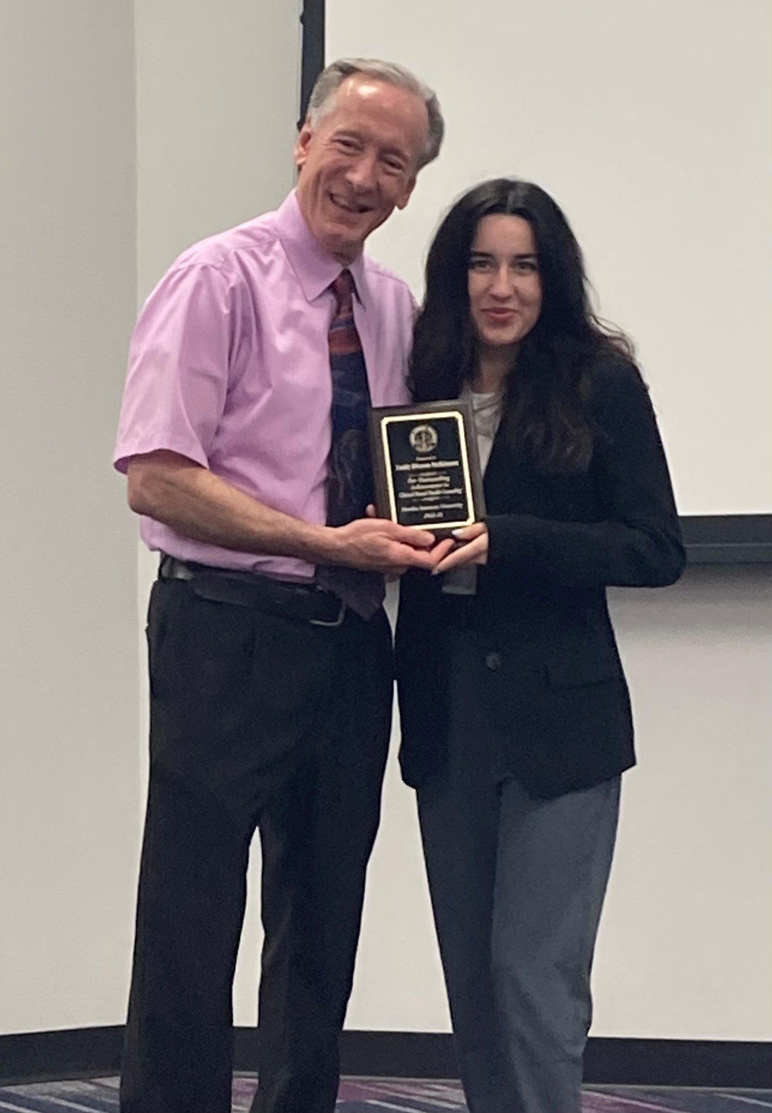 Student posing with professor and she receives an award