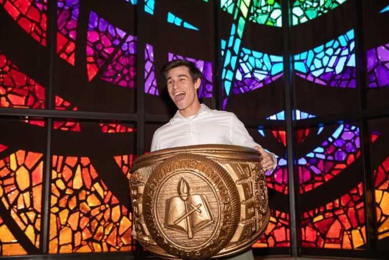 Adrian Gonzales, holding a giant model class ring in the Logsdon Chapel.