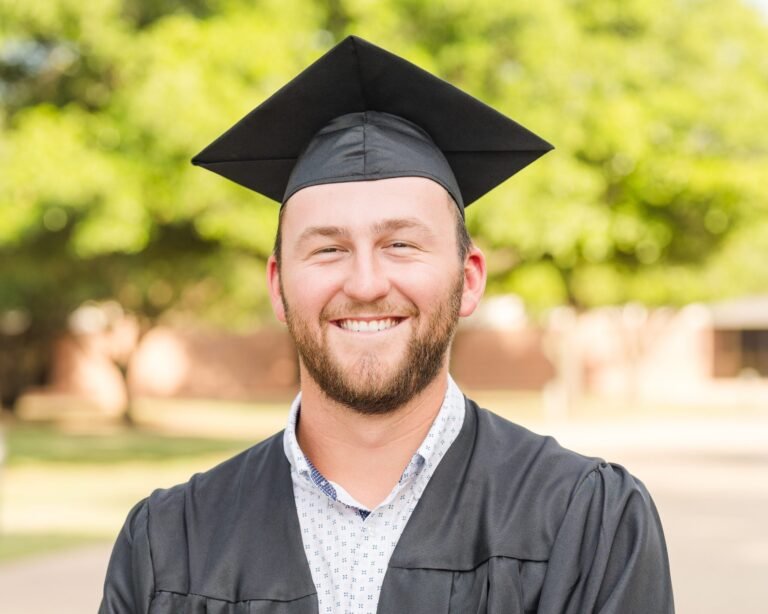 Grant Mitzelfelt smiles wearing his graduation cap and gown.