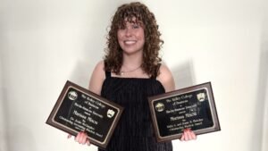 Marissa posing with two of her awards: The Dr. Jodie McGaughey Outstanding Accounting Student Award, and the Ruby A. and Jesse N. Fletcher Outstanding Student Award.