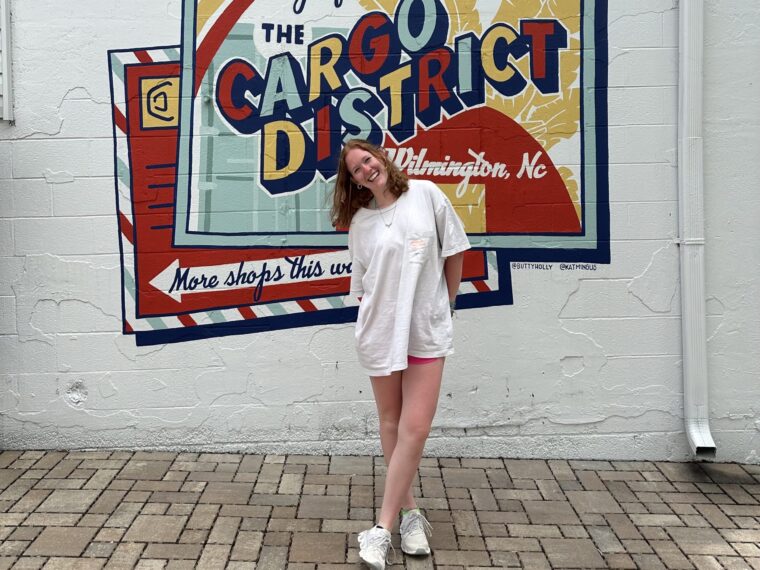 Mandy Jo stands in front of a mural painted on a walk in Wilmington, NC.