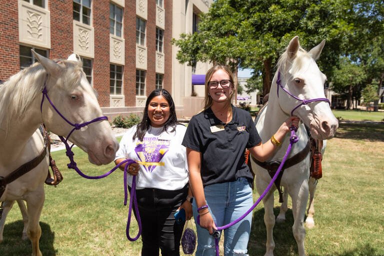 Student worker Sayler Beerwinkle poses with her supervisor, Sarah Palma '22/'24, after gathering content for a social media post.