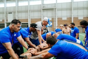 BYU football players push through a strength challenge during a training session, where HSU alumnus Tim Ismail contributes to developing the team’s toughness and discipline.