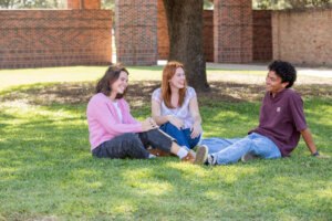 Students sitting outside under a tree laughing together