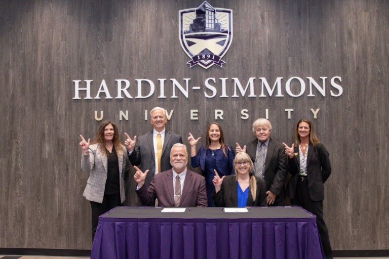 Staff members hold up the school hand signal.