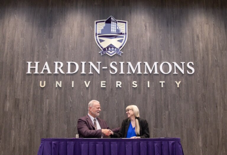 Two staff members shake hands at a table.