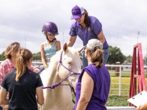 Small girl on horse with other adults helping her.