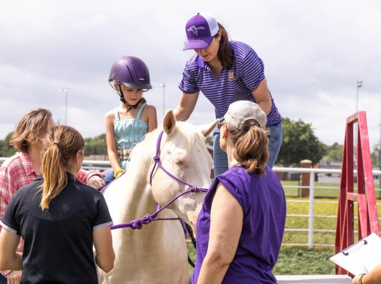Small girl on horse with other adults helping her.