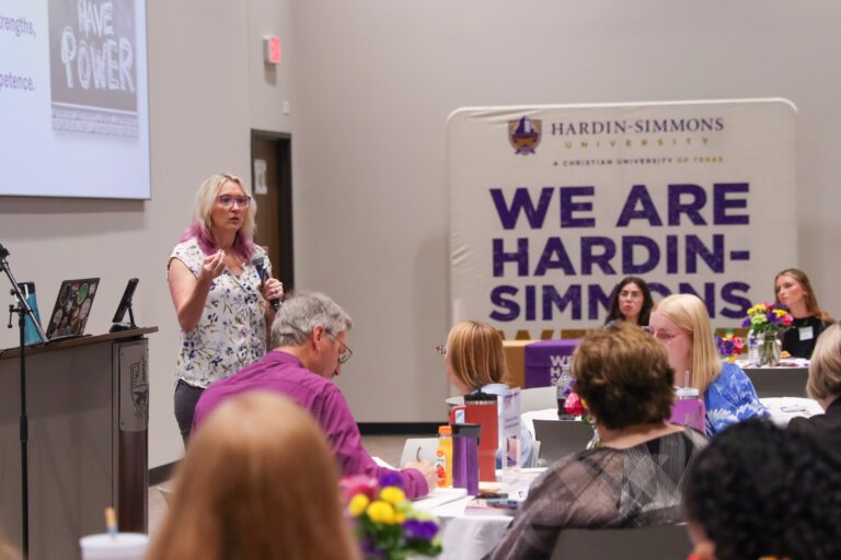 A presenter talks at a conference to an audience.