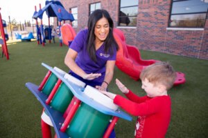 Student plays with a child on a playground.